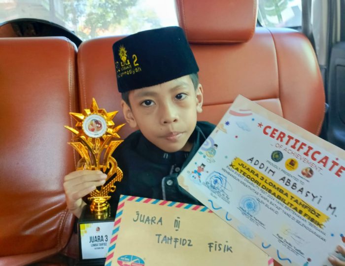 Addin Abbasyi Muhammad, seorang siswa berkebutuhan khusus dari SD Muhammadiyah 2 Sidoarjo saat menunjukkan piala dalam lomba Tahfizhul Qur'an